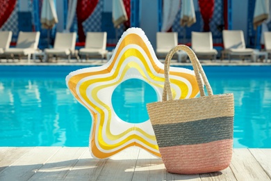 Beach bag and inflatable ring near swimming pool outdoors