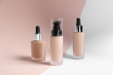 Photo of Bottles of skin foundation on color background. Makeup product