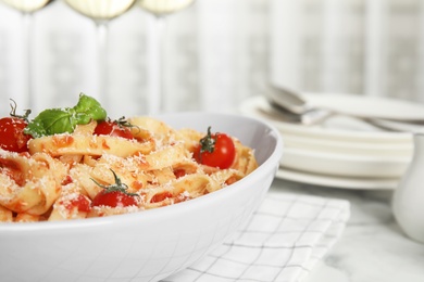 Tasty pasta with tomatoes, cheese and basil on white marble table, closeup