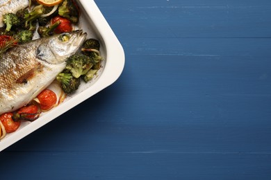 Photo of Delicious fish with vegetables and lemon in baking dish on blue wooden table, top view. Space for text