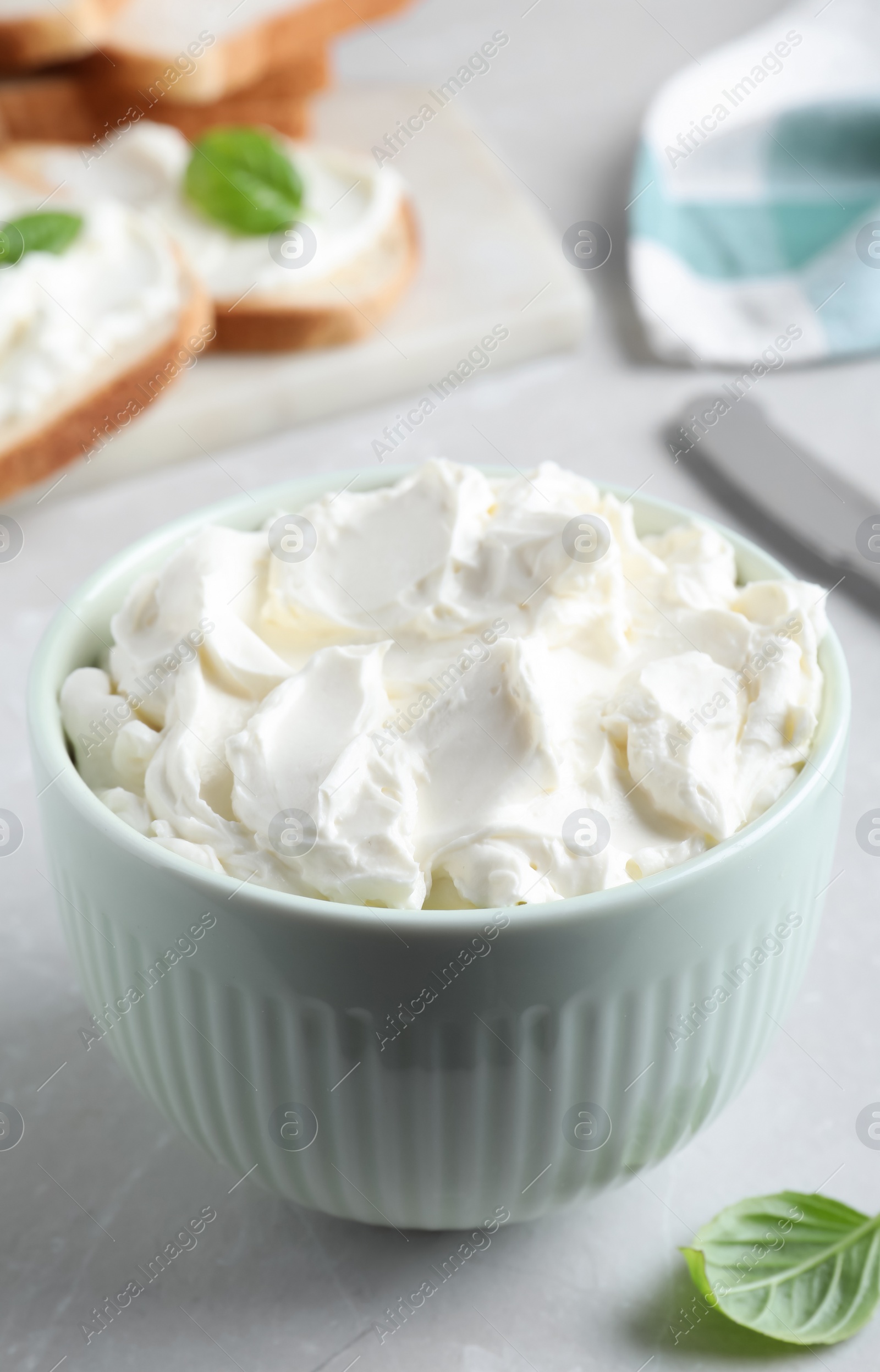 Photo of Bowl of tasty cream cheese on grey table
