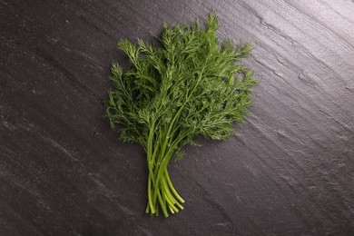 Photo of Sprigs of fresh dill on dark textured table, top view