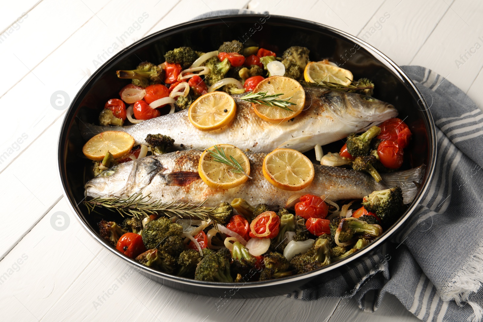 Photo of Baked fish with vegetables, rosemary and lemon on white wooden table, closeup