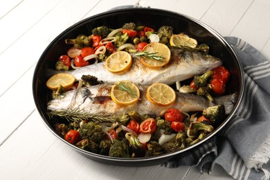 Photo of Baked fish with vegetables, rosemary and lemon on white wooden table, closeup