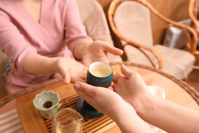 Photo of Master giving freshly brewed tea to guest during ceremony at table, closeup