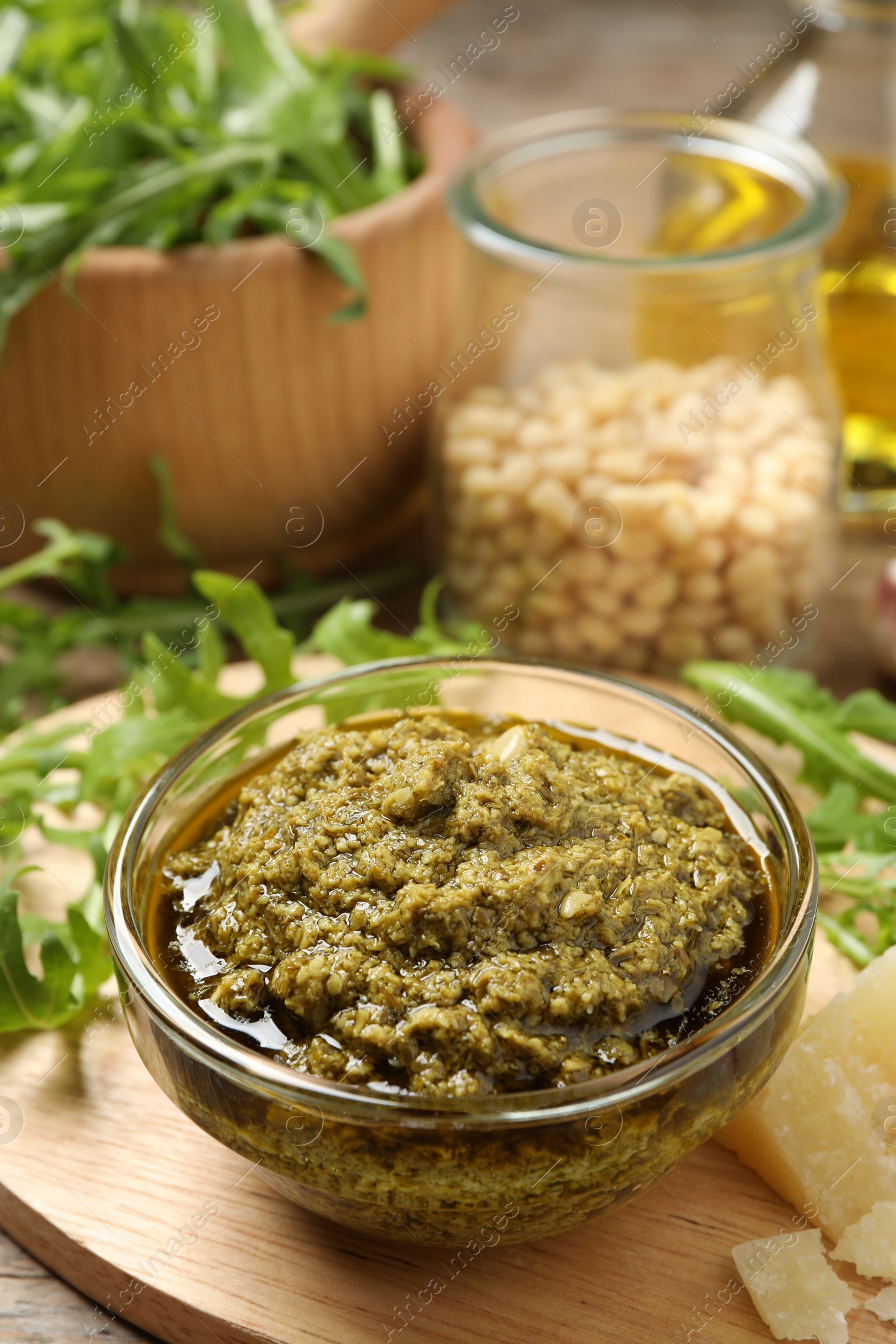 Photo of Bowl of tasty arugula pesto and ingredients on table