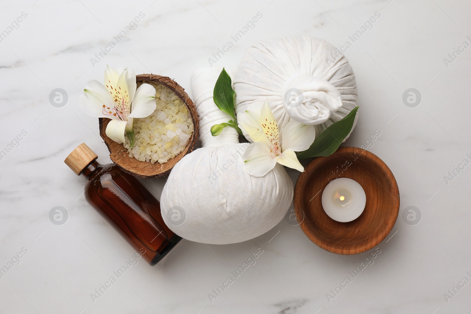 Photo of Spa composition with burning candle and herbal bags on white marble table, flat lay