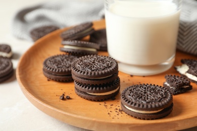 Plate with chocolate sandwich cookies and milk on table