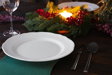 Plate, cutlery, glass and festive decor on wooden table