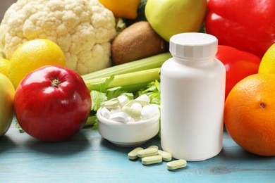 Photo of Dietary supplements. Bottle and bowl with different pills near food products on light blue wooden table