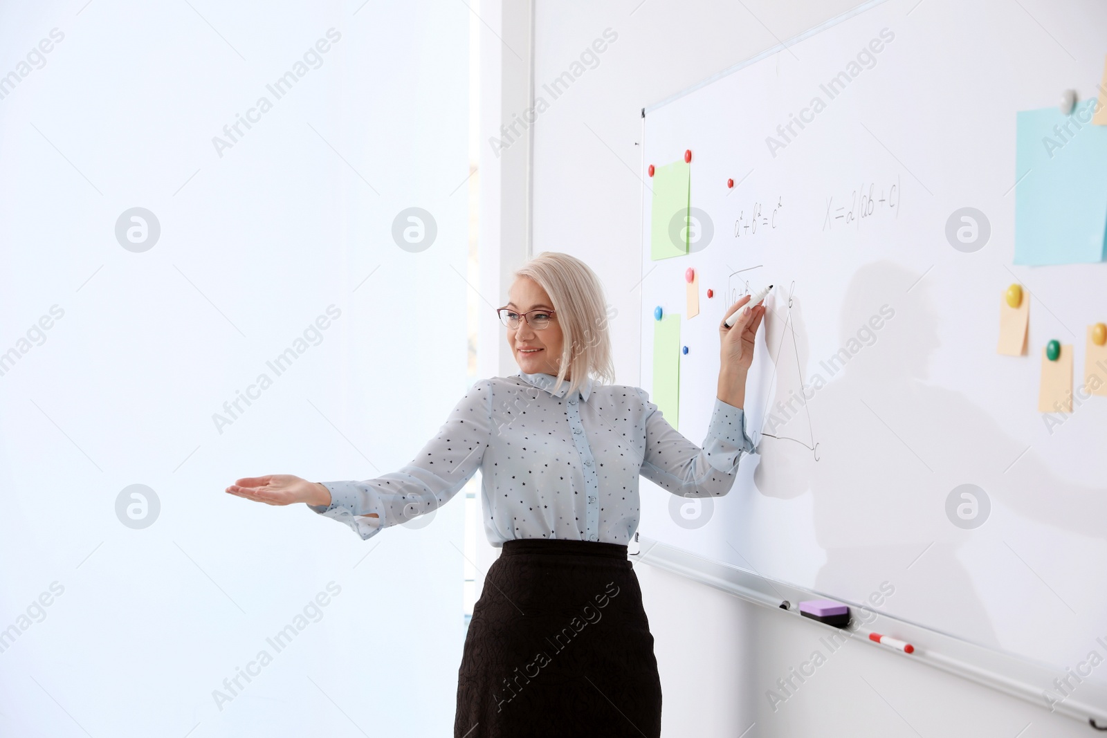 Photo of Mature teacher near whiteboard in modern classroom