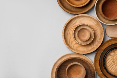 Set of different wooden dishes on light grey background, flat lay with space for text. Cooking utensils