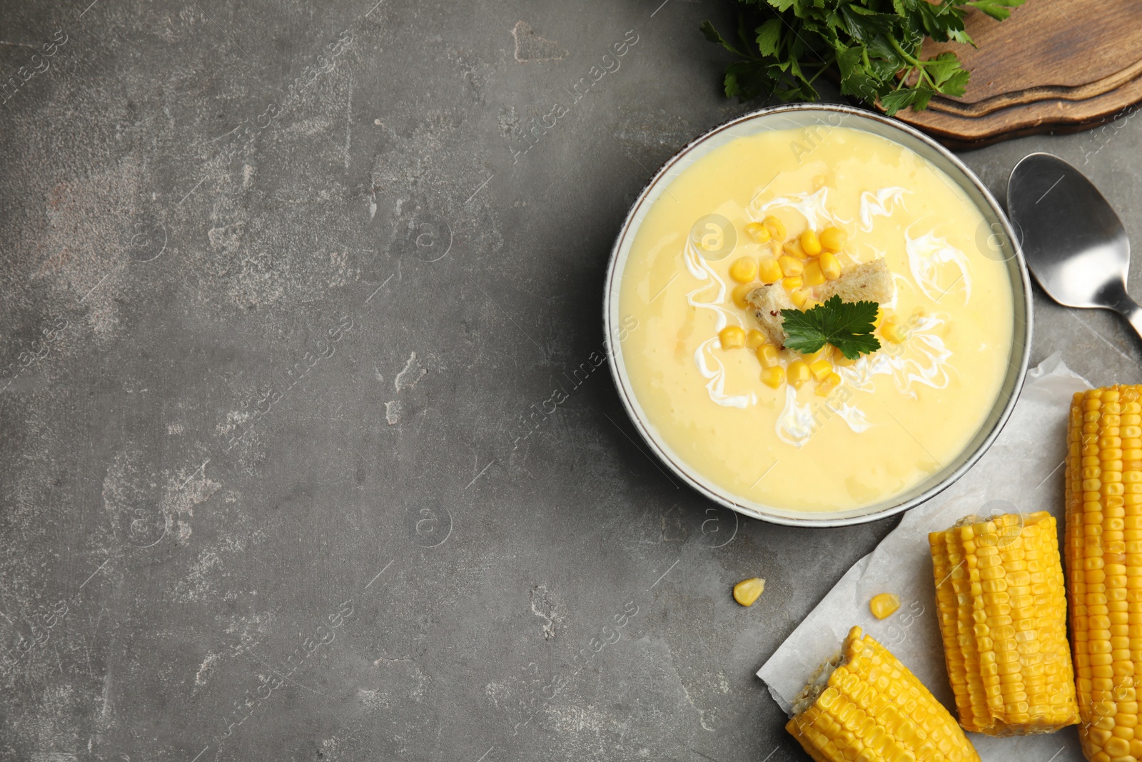 Photo of Delicious corn cream soup served on grey table, flat lay. Space for text