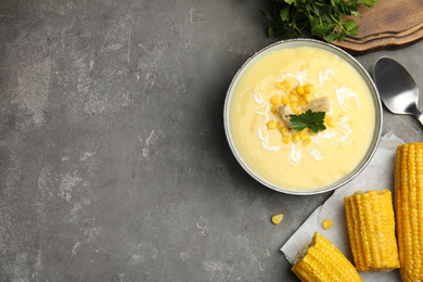 Delicious corn cream soup served on grey table, flat lay. Space for text