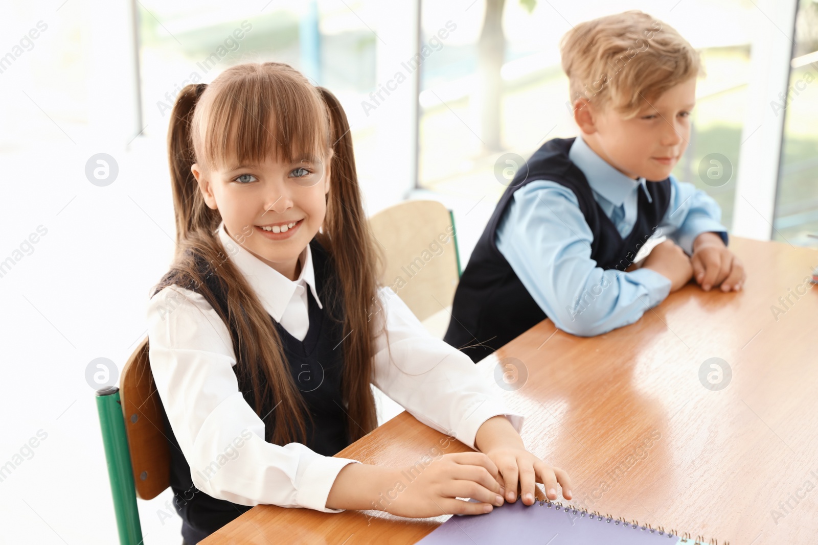 Photo of Little children in classroom. Stylish school uniform