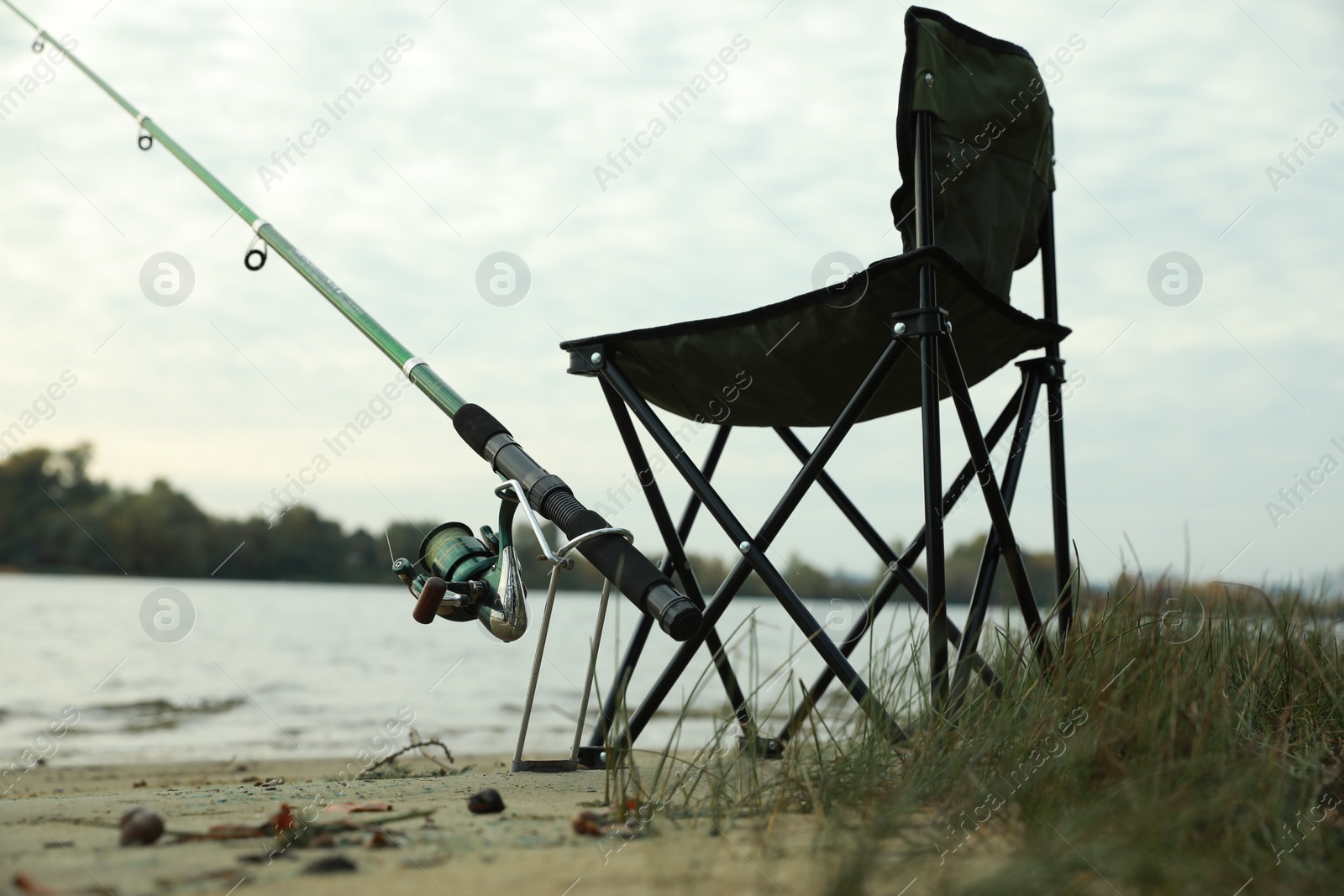 Photo of Folding chair and fishing rod at riverside, low angle view