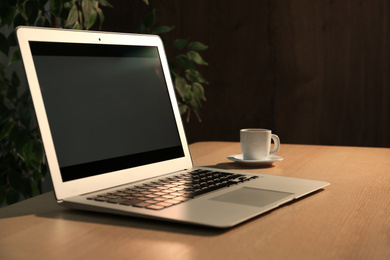 Photo of Modern laptop and cup of coffee on desk in office. Space for design