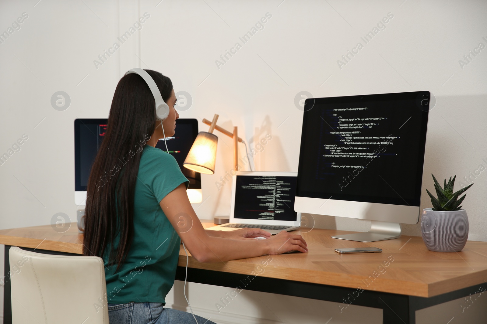 Photo of Programmer with headphones working at desk in office