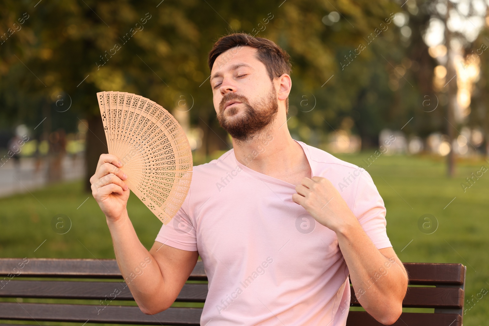 Photo of Man with hand fan suffering from heat outdoors