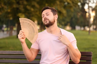 Man with hand fan suffering from heat outdoors