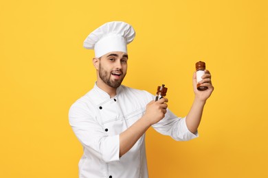 Photo of Professional chef with shakers on yellow background