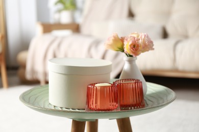 Photo of Box, candles and beautiful flowers on side table at home