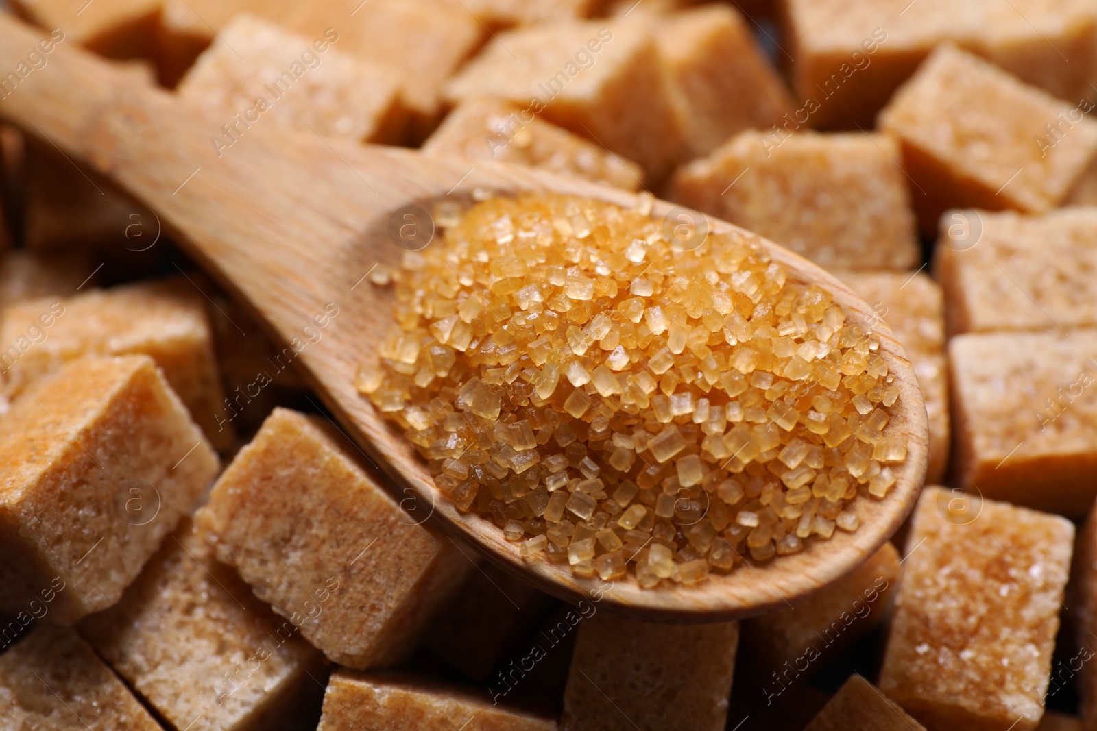 Photo of Wooden spoon on brown sugar cubes, closeup