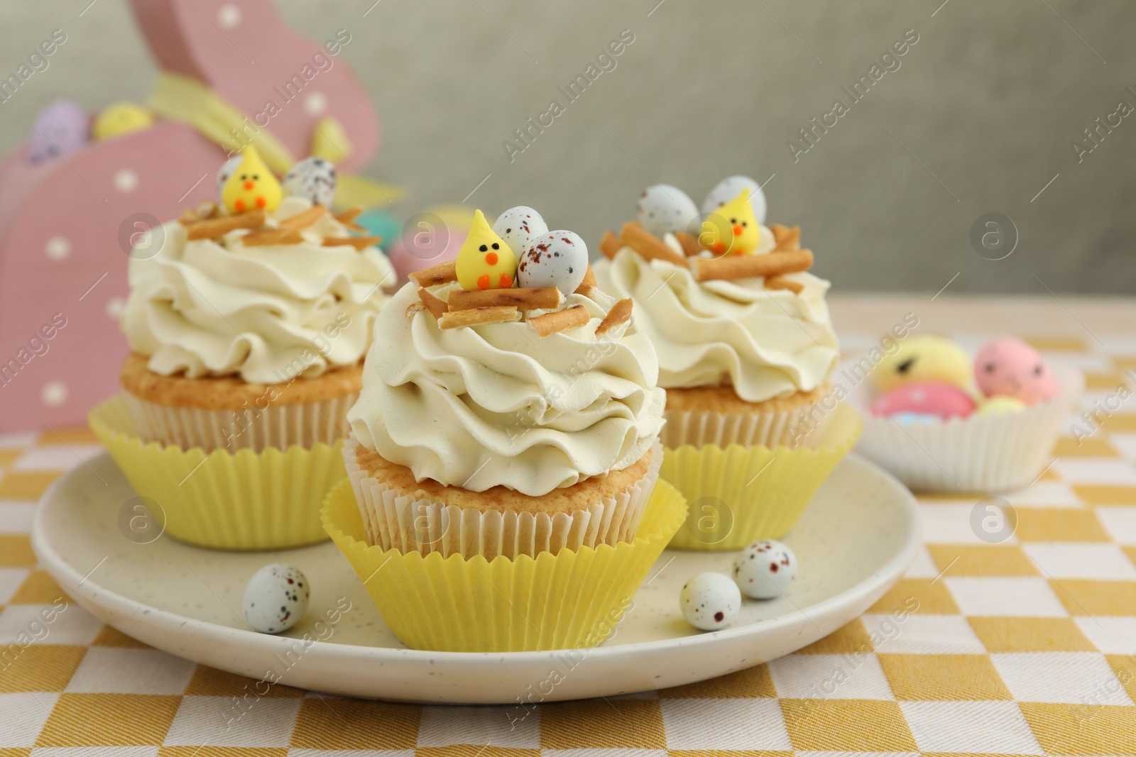 Photo of Tasty Easter cupcakes with vanilla cream on table, closeup