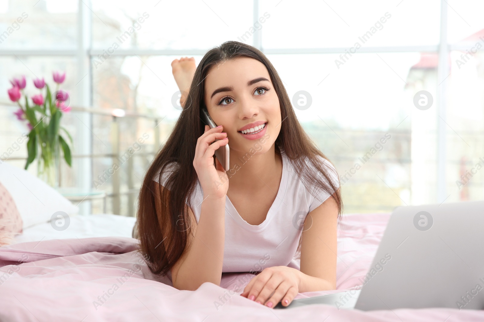 Photo of Attractive young woman talking on mobile phone at home