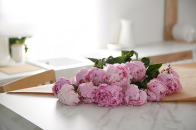 Photo of Bouquet of beautiful pink peonies on table in kitchen