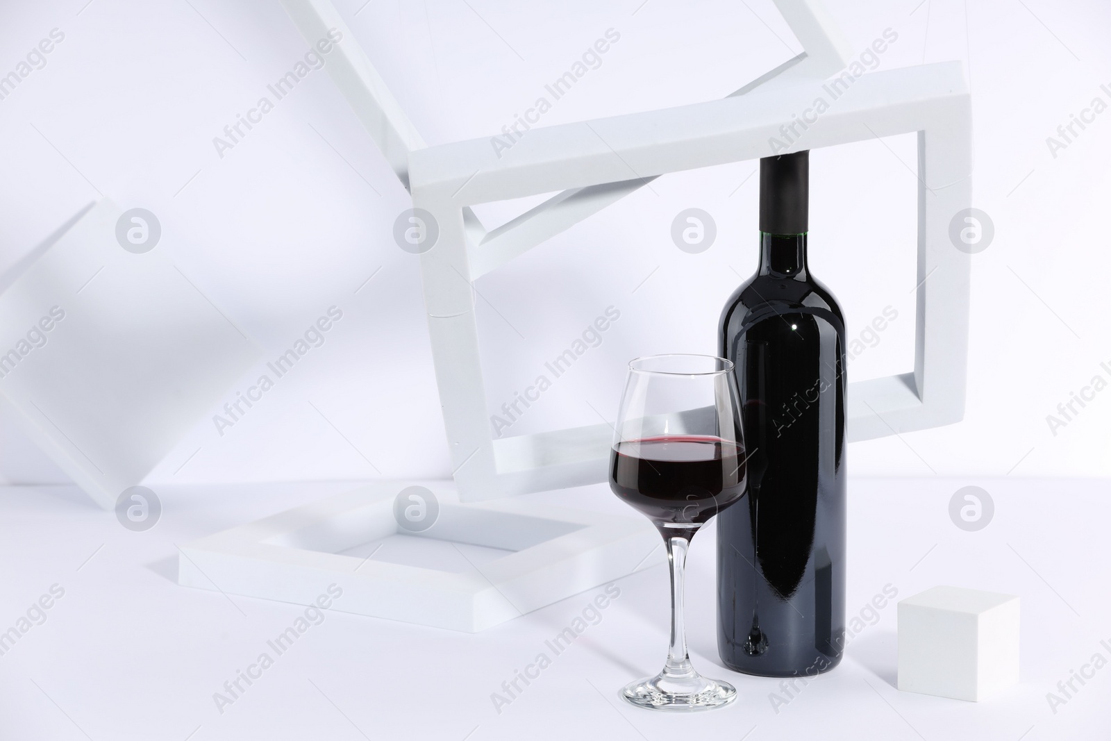Photo of Stylish presentation of delicious red wine in bottle and glass on white background. Space for text