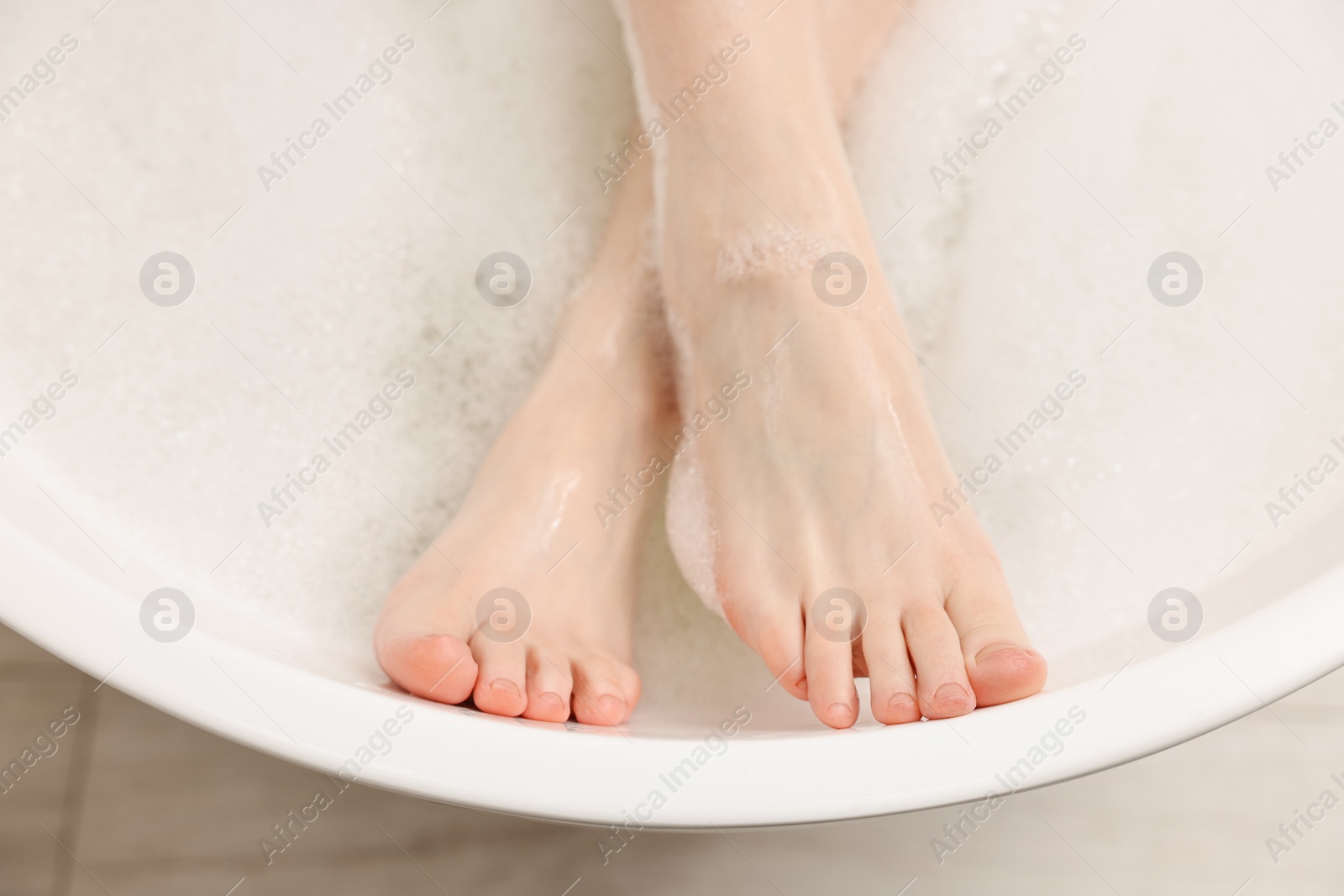 Photo of Woman taking bath with foam in tub, top view