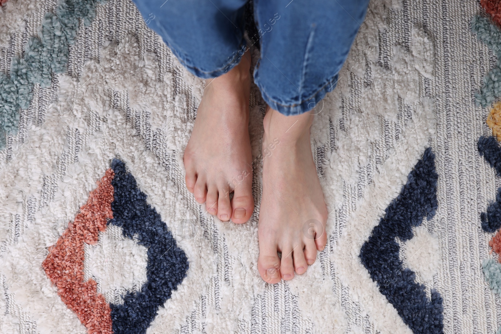 Photo of Woman on carpet with pattern at home, top view