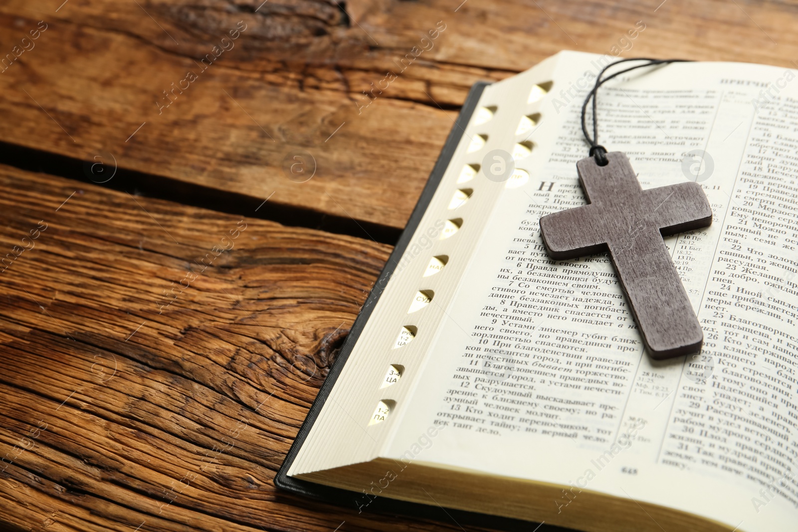 Photo of MYKOLAIV, UKRAINE - DECEMBER 20, 2021: Christian cross and Bible on wooden table, space for text