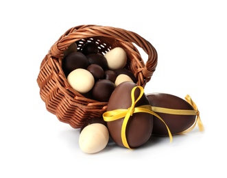 Photo of Wicker basket with sweet chocolate Easter eggs on white background