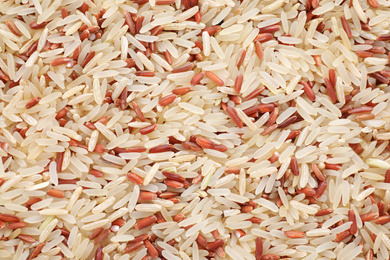 Photo of Mix of brown and polished rice as background, top view