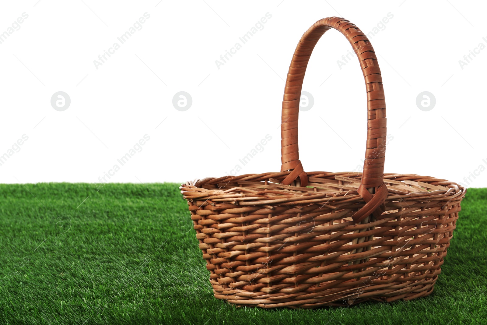 Photo of Empty wicker basket on green lawn against white background. Space for design. Easter item