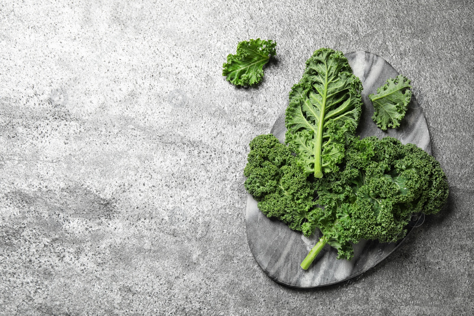 Photo of Fresh kale leaves on grey table, flat lay. Space for text