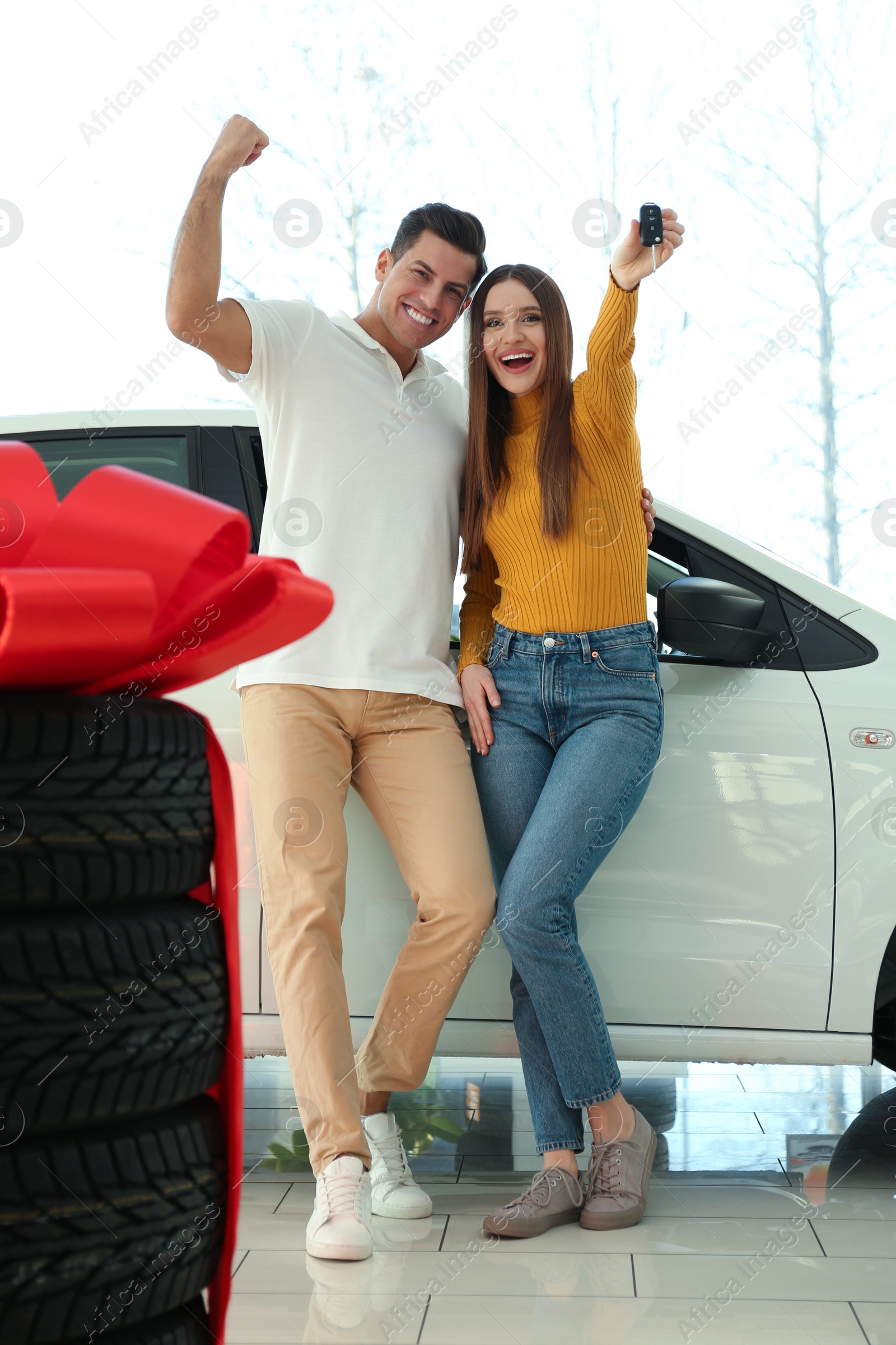 Photo of Happy couple with car key in modern auto dealership