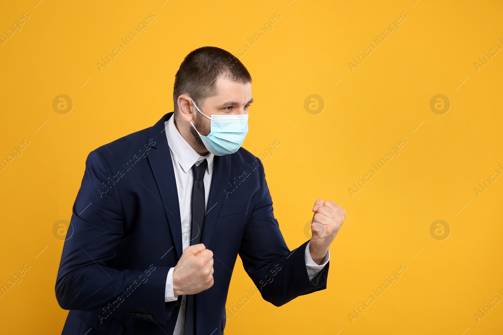 Photo of Businessman with protective mask in fighting pose on yellow background, space for text. Strong immunity concept
