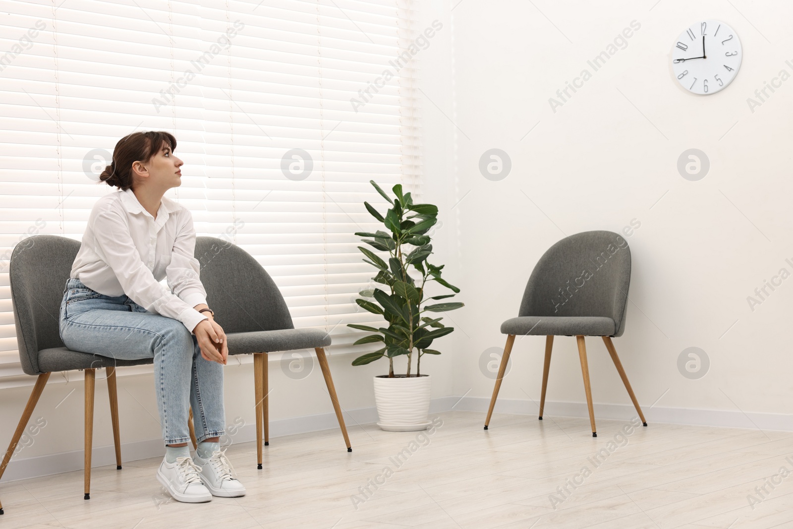 Photo of Woman sitting on chair and waiting for appointment indoors