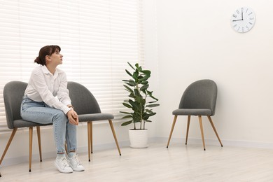 Woman sitting on chair and waiting for appointment indoors