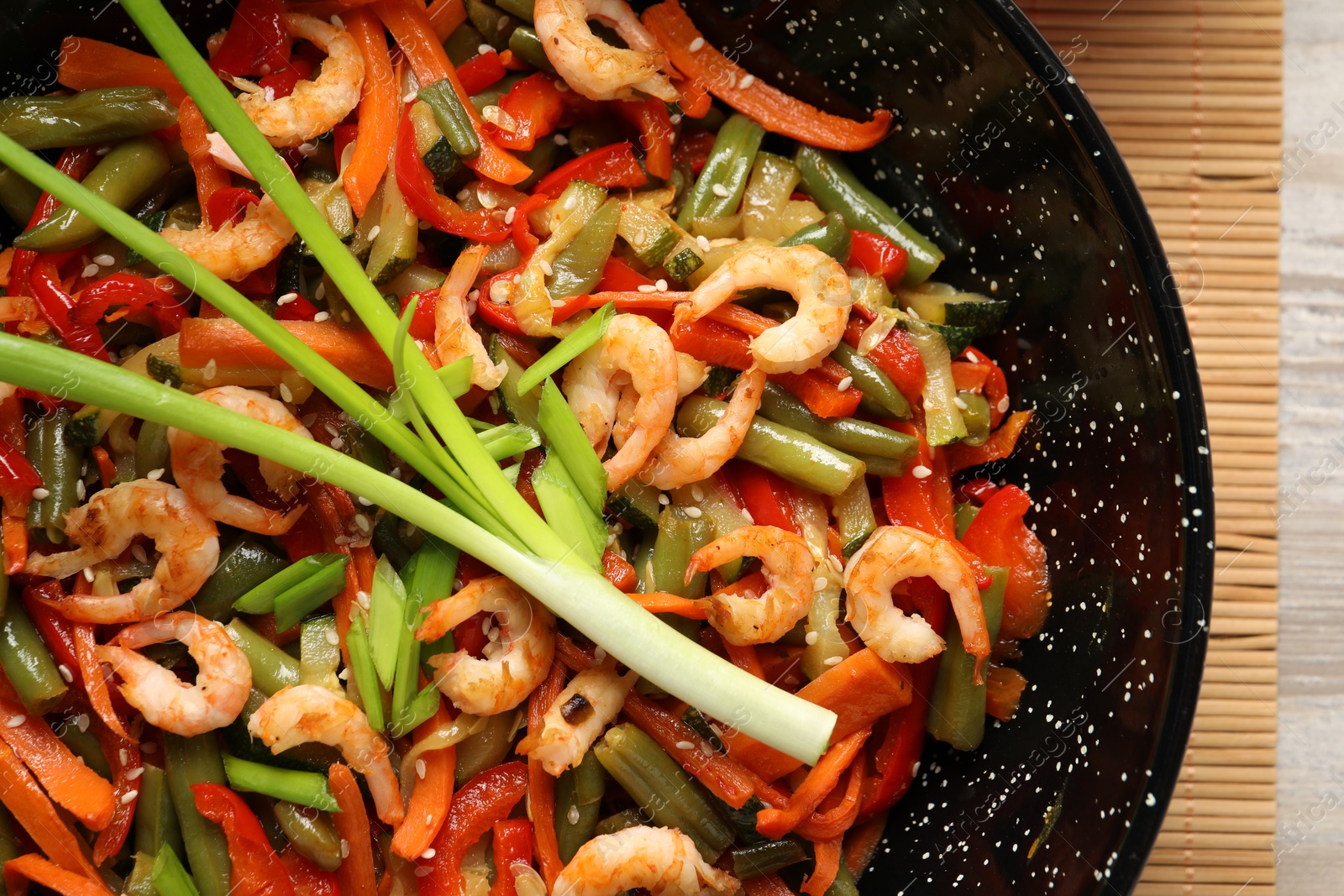 Photo of Shrimp stir fry with vegetables in wok on table, top view