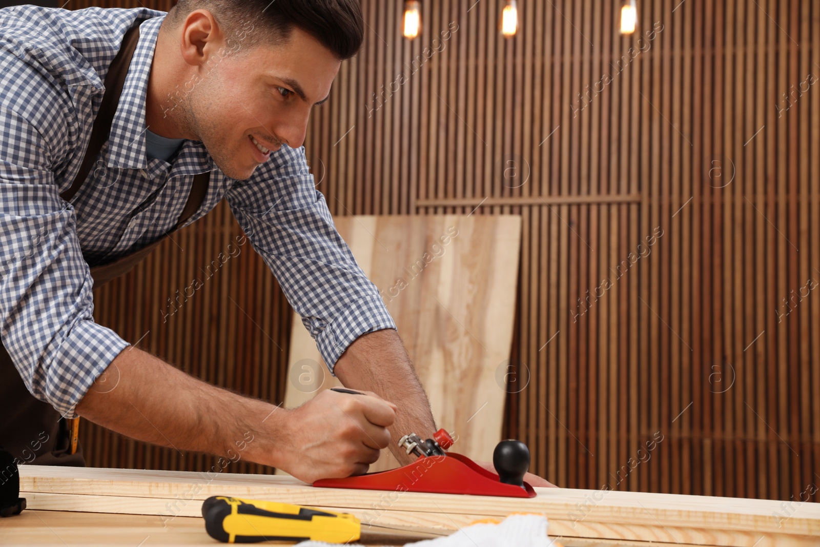 Photo of Handsome carpenter working with timber at table indoors