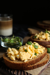 Tasty scrambled egg sandwich on wooden board