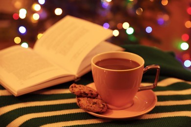 Photo of Cup of delicious hot cocoa, cookies and book on colorful cloth. Space for text