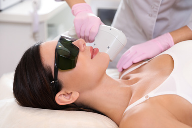 Photo of Young woman undergoing laser epilation procedure in beauty salon