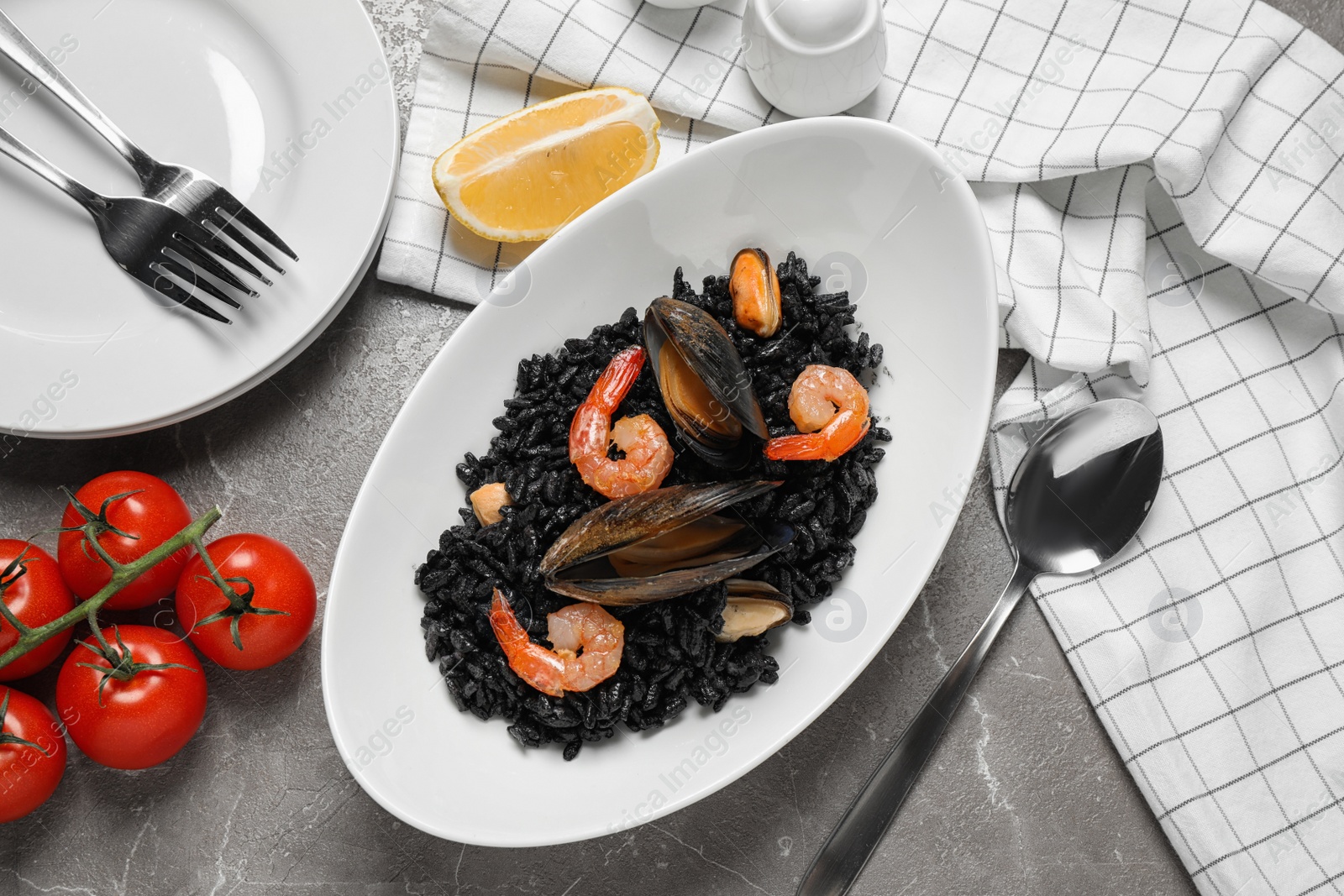 Photo of Delicious black risotto with seafood served on marble table, flat lay