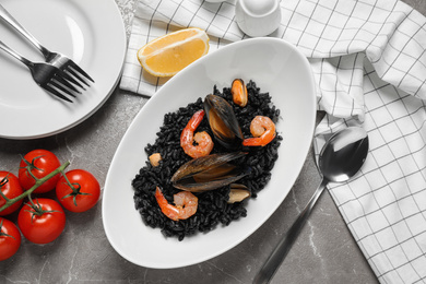 Delicious black risotto with seafood served on marble table, flat lay