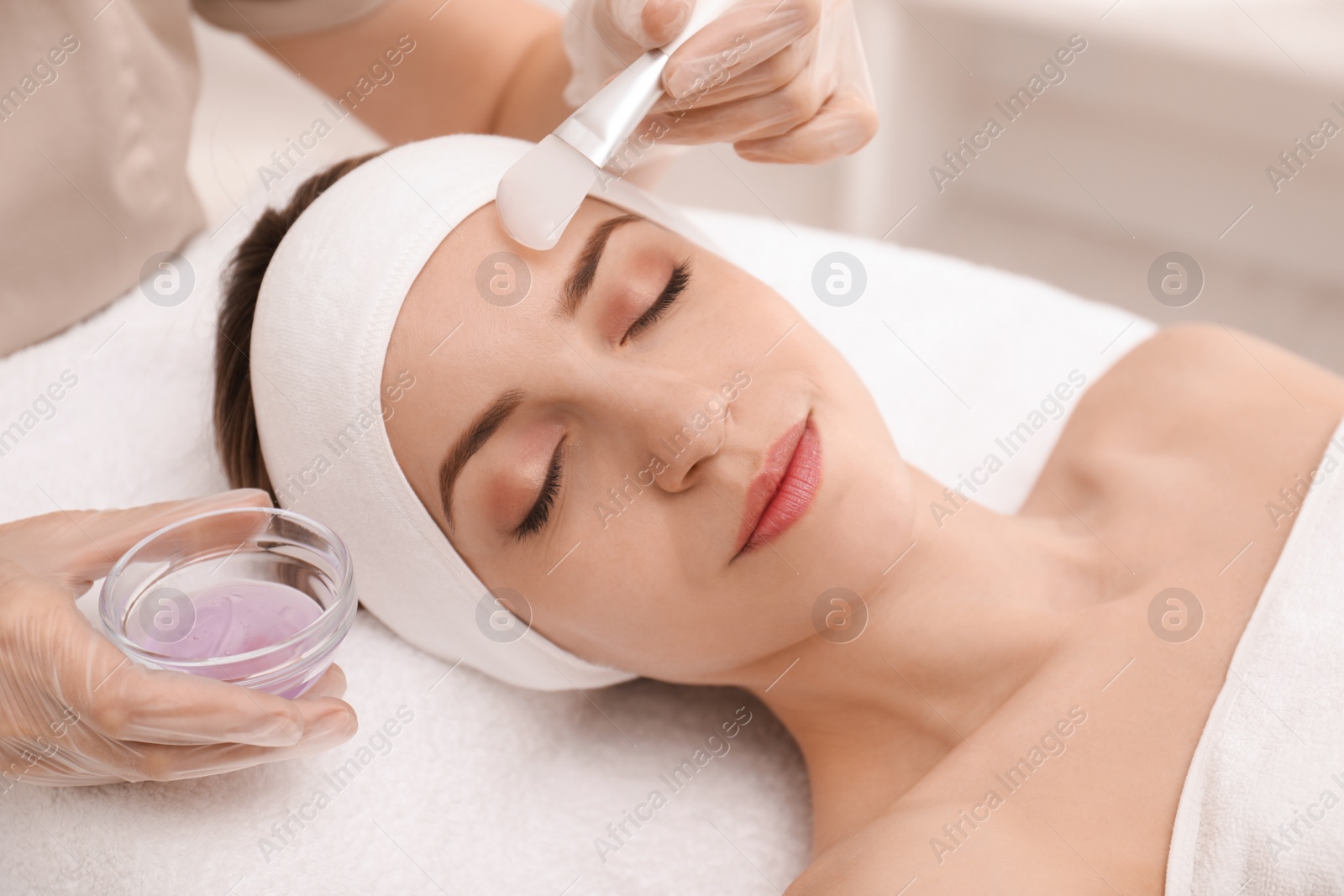 Photo of Young woman during face peeling procedure in salon